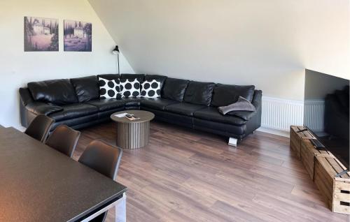 a living room with a black leather couch and a table at Penthouse in Hobro