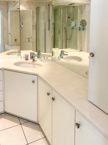 a bathroom with two sinks and two mirrors at Hotel ALMA in Wassenberg