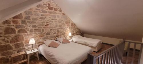 two beds in a room with a stone wall at Villa Varco in Auxonne