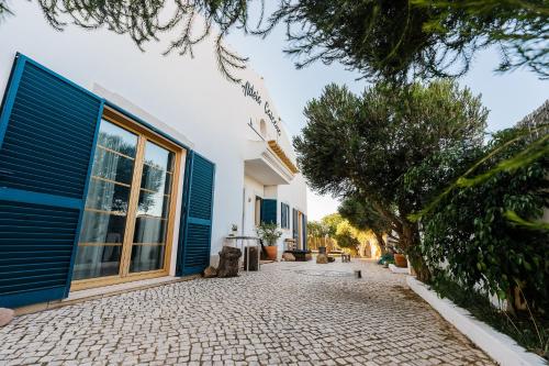 a house with a blue door and a stone driveway at Aldeia Caiçara Surf House in Sagres