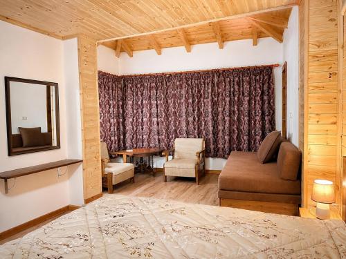 a bedroom with a bed and a couch and a window at Boutique Vila ERI in Gjirokastër