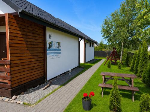 a picnic table and a bench next to a building at Domki letniskowe MagNat 700m od morza! in Rusinowo