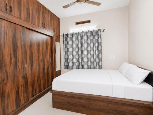 a bedroom with a bed and a wooden door at SV Serviced Apartments in Chikmagalūr