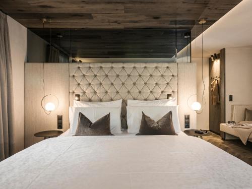a bedroom with a large white bed with two pillows at Hotel Bergkristall Zillertal - Adults Only in Hippach