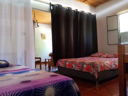 a bedroom with two beds and a black curtain at Brisas de la Bujona in Honda