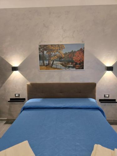 a bedroom with a blue bed and a painting on the wall at Gli Amici della Puglia 2 in Taranto