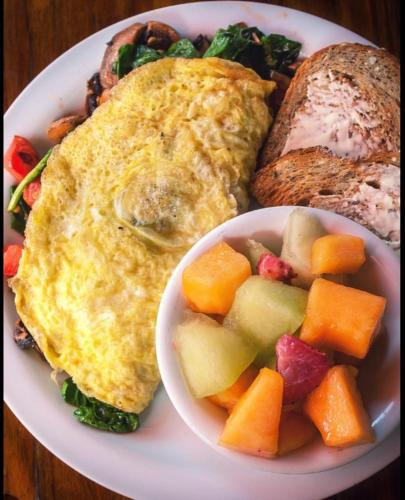 a plate of breakfast food with a fried egg and a bowl of fruit at Beal Mall & Hotel in Arua