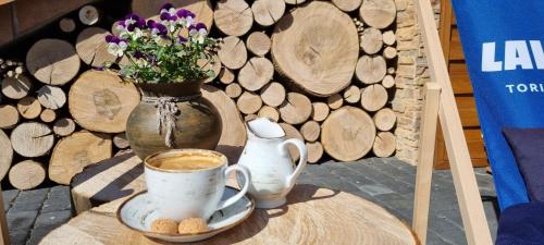 a table with a cup of coffee and a vase with flowers at Zielone Wzgórza - Centrum Soliny - SPA 695-744-679 in Solina