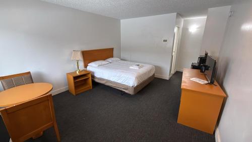 a room with a bed and a desk and a television at Midtown Inn Saskatoon in Saskatoon
