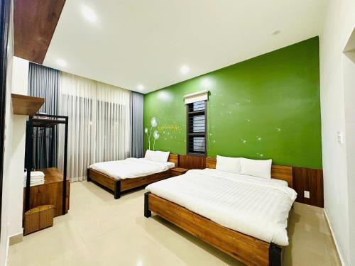 a bedroom with two beds and a green wall at Lala VILLA ĐÀ LẠT in Da Thien
