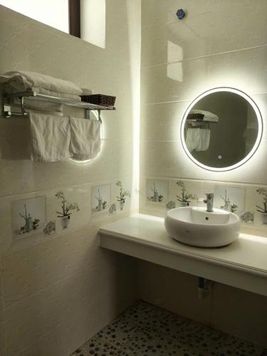 a white bathroom with a sink and a mirror at Nhà khách 705 in Mộc Châu