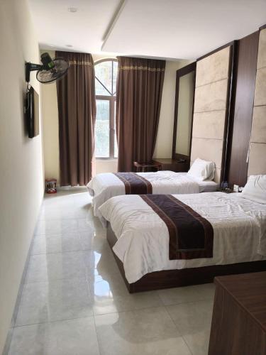 a hotel room with two beds and a large window at Nhà khách 705 in Mộc Châu
