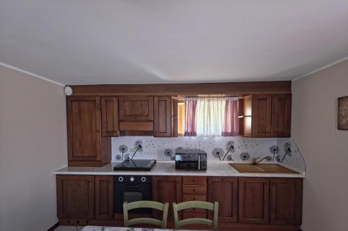 a kitchen with wooden cabinets and a sink and a stove at Casa con giardino e garage vicino alle piste in San Pietro