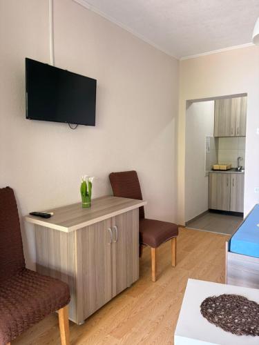a living room with two chairs and a tv on the wall at Apartments President in Star Dojran