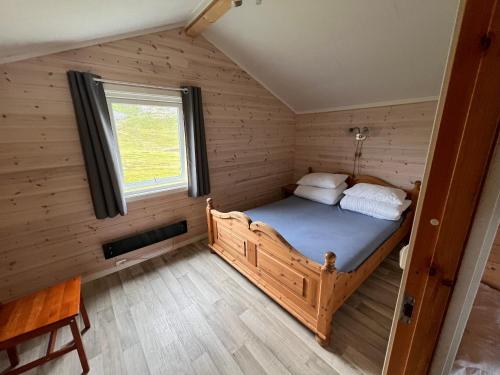 a small bedroom with a bed in a wooden house at Hytte Camp Nordkapp - Blue in Skarsvåg