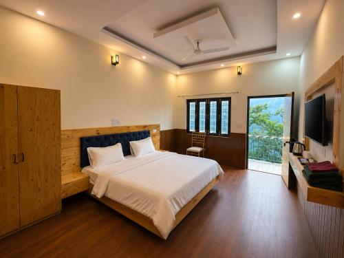 a bedroom with a large bed and a television at Cross Hill House Mussoorie in Mussoorie
