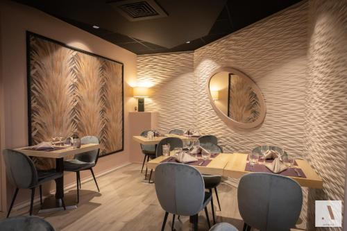 a restaurant with tables and chairs and a mirror at Kyriad Hotel Nevers Centre in Nevers