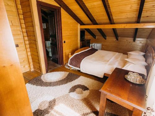 a bedroom with a bed and a table in a room at Complex Turistic Le Baron Vatra Dornei in Vatra Dornei