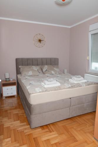 a bed in a bedroom with a clock on the wall at Apartman "JOKA" in Đakovo