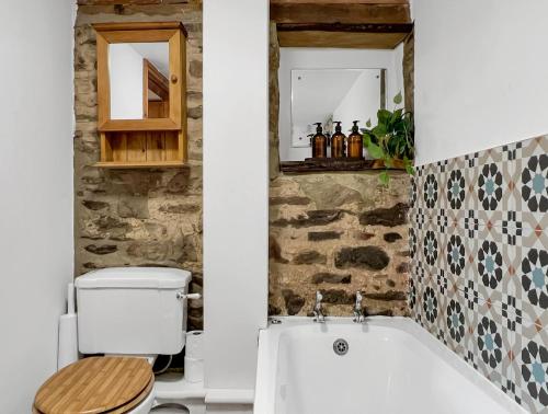 a bathroom with a toilet and a bath tub at Smiddy Cottage Hawkridge in Dulverton