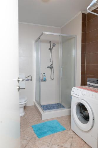 a bathroom with a shower and a washing machine at Apartman "JOKA" in Đakovo