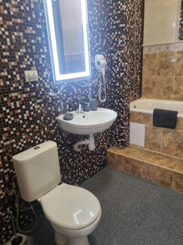 a bathroom with a toilet and a sink and a tub at Hotel Complex Uhnovych in Ternopil