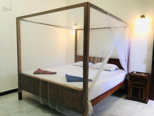 a bedroom with a canopy bed with white sheets at Yellow bay inn in Arugam Bay