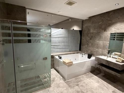 a bathroom with a tub and a shower and a sink at شقق ثري ستار للشقق المخدومة 5 in Al Kharj