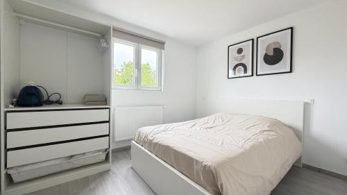 a white bedroom with a bed and a dresser at L'Annexe in Arlon