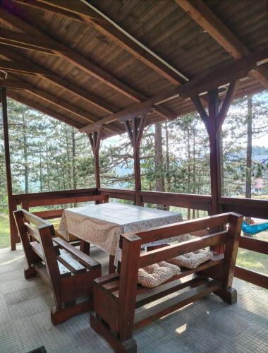 a picnic table and benches on a screened porch at Vikendica Vidik in Divčibare