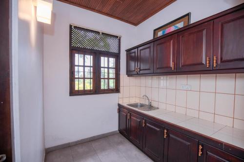 a kitchen with wooden cabinets and a sink and a window at KapuGedara297 in Galle