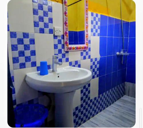 a blue and white bathroom with a sink and a mirror at Furaha Rena -Kendwa in Kendwa