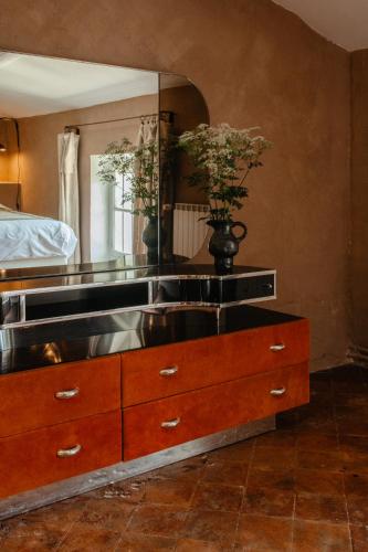 a dresser with a mirror and a vase with flowers on it at Casa tudo bem in Pernes-les-Fontaines
