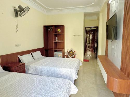 a hotel room with two beds and a flat screen tv at Huệ Vinh Hotel in Cửa Lô