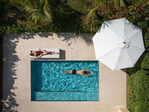 an overhead view of a swimming pool with a person and an umbrella at Sofitel Ras Al Khaimah Al Hamra Beach Resort in Ras al Khaimah
