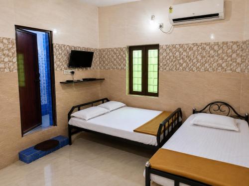 a bedroom with two beds and a tv on the wall at C Gowri Lodge in Vellore