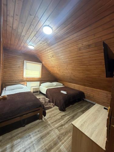 two beds in a room with wooden walls at Садиба Сойми in Soymy
