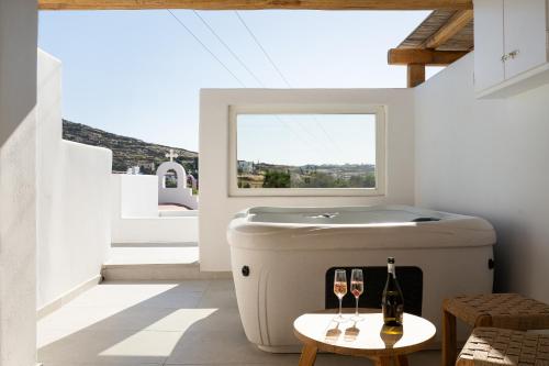 a hot tub in a room with two glasses of wine at Oliving Mykonos Luxury Suites in Klouvas