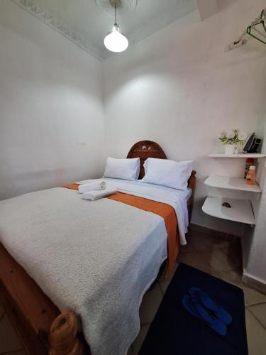 a bedroom with a bed with white and orange sheets at holm's home studio in Diani Beach