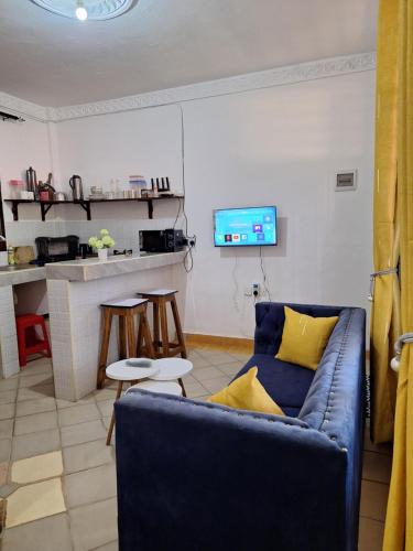 a living room with a blue couch and a tv at holm's home studio in Diani Beach