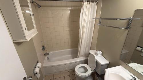 a bathroom with a toilet and a tub and a sink at Midtown Inn Saskatoon in Saskatoon