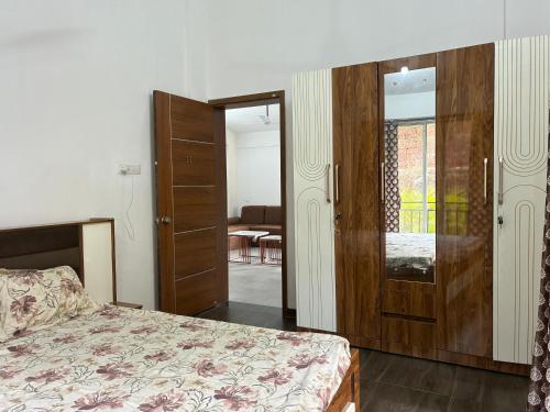 a bedroom with a bed and a wooden cabinet and a door at Casa asud Dapoli in Dapoli