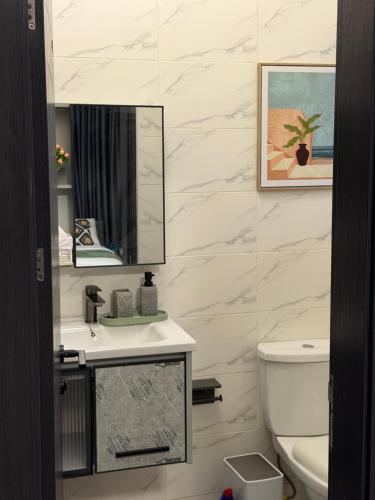 a bathroom with a sink and a mirror and a toilet at F&F Villa in Tema
