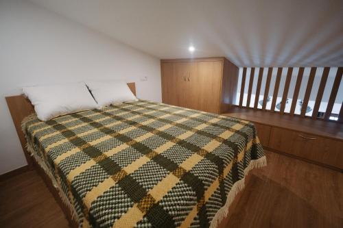a bedroom with a bed with a checkered blanket at Casa do Javali 3 in Bragança
