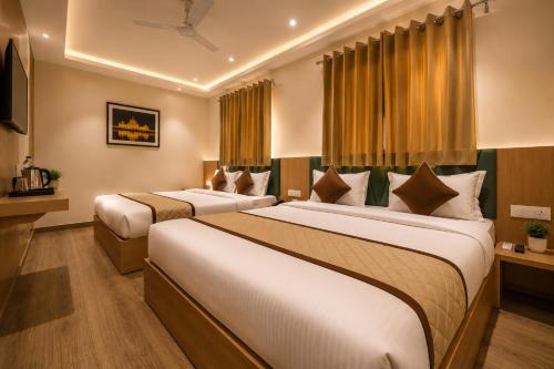 two beds in a hotel room with yellow curtains at Hotel Nayyar Regency Near Golden temple in Amritsar
