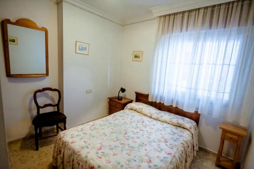 1 dormitorio con cama, espejo y silla en MAQUINILLA PORTAL 4A, en Nerja