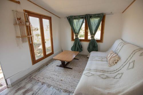 une chambre avec un lit, une table et des fenêtres dans l'établissement cabane des vignes, à Cotignac