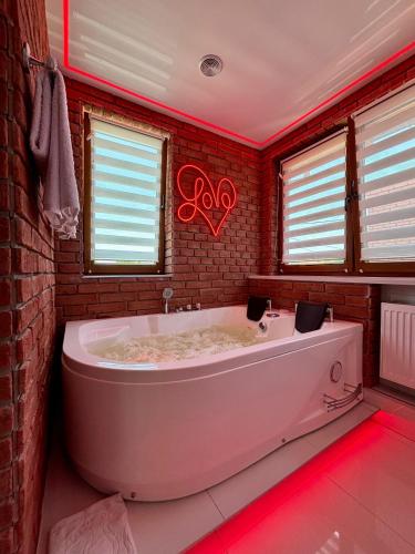 a large white tub in a bathroom with red lights at Apartament "Loft Love" Jacuzzi SPA z dużą wanną z hydromasażem dla Dwojga in Gniezno