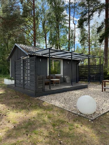 a small cabin with a black roof and a table at Pussala Latgalē in Ezerukiņi