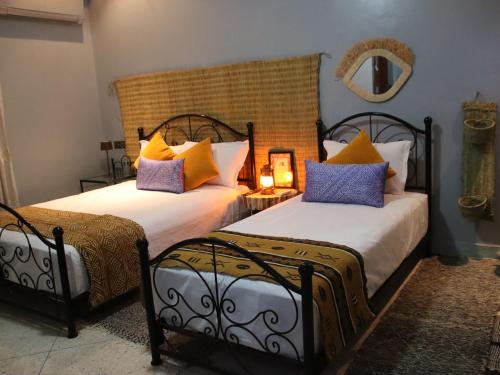 a bedroom with two beds and a mirror at Riad Perlamazigh in Zagora